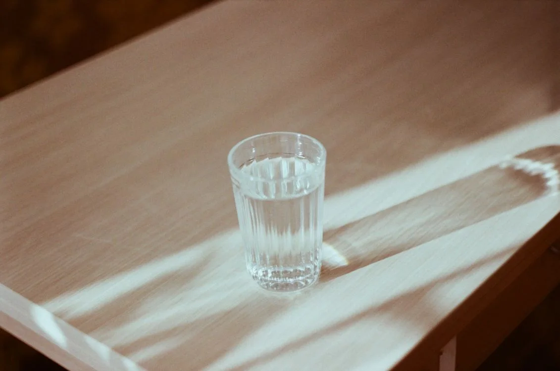 A clear glass filled with drinking water on a wooden table